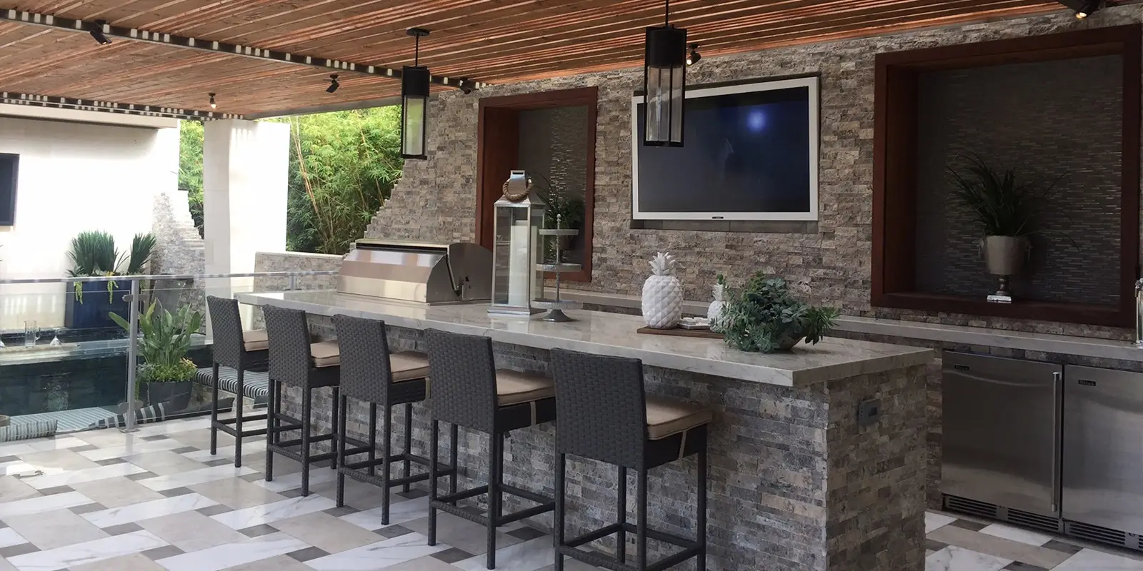 Custom-built outdoor kitchen in Florida featuring natural stone tiles, showcasing a blend of modern design and timeless elegance. Florida Design Works.